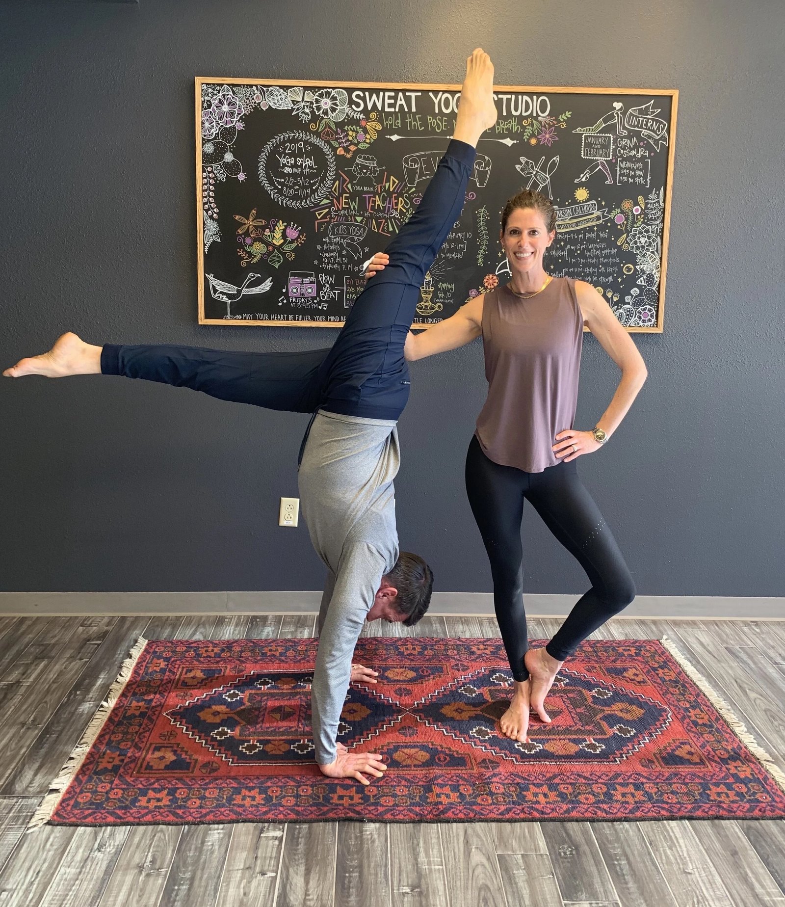A student held in a spotted handstand at SWEAT Yoga Studio in Albuquerque